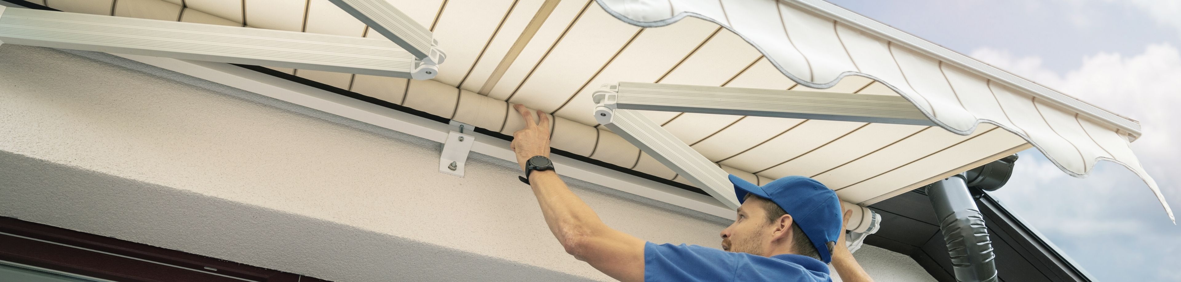 Man met pet op maakt zonwering schoon