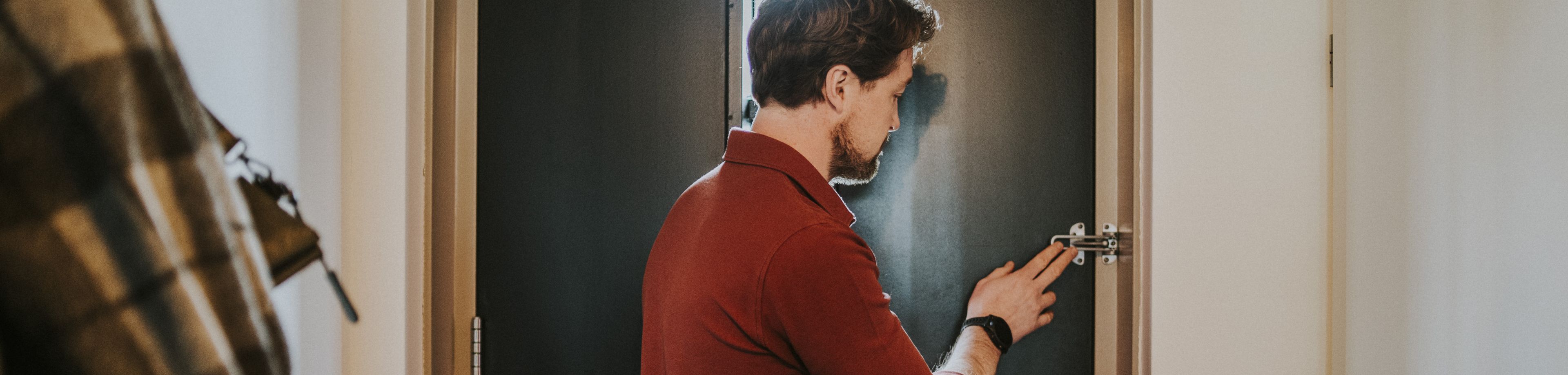 Een man doet de kierstandhouder aan de binnenkant van de voordeur.