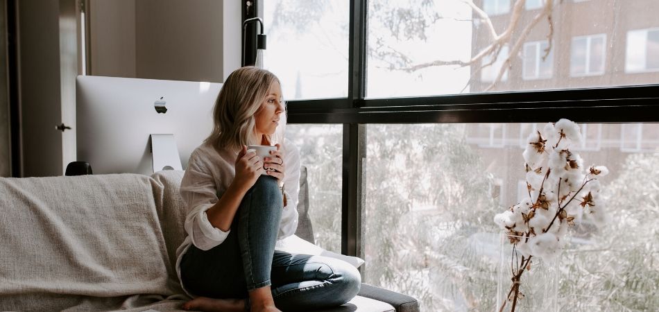 Vrouw die in de vensterbank zit en uit het raam kijkt