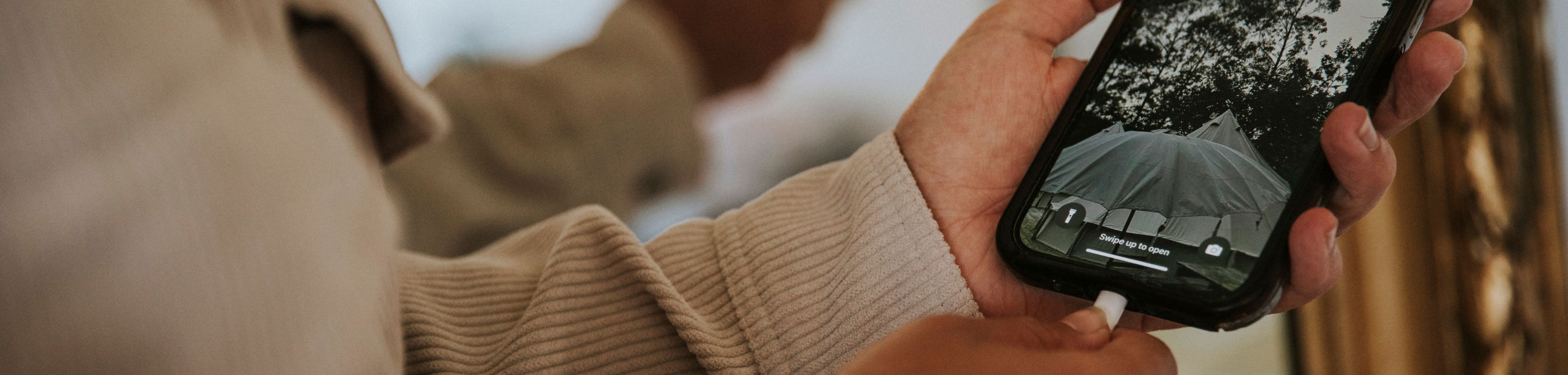 Iemand steekt de laadkabel in de oplaadpoort van een smartphone.