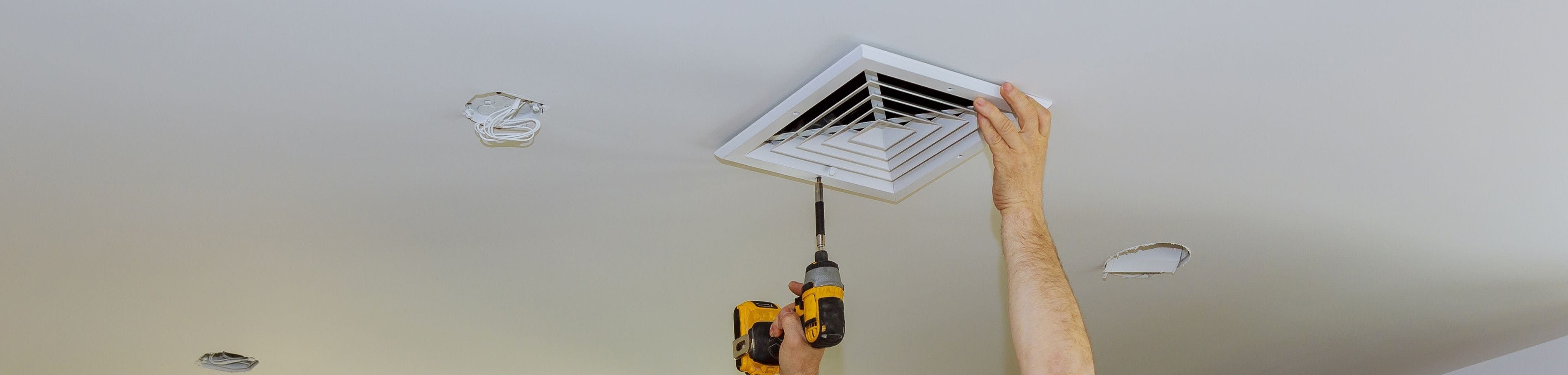 Man bevestigt ventilatierooster in een plafond