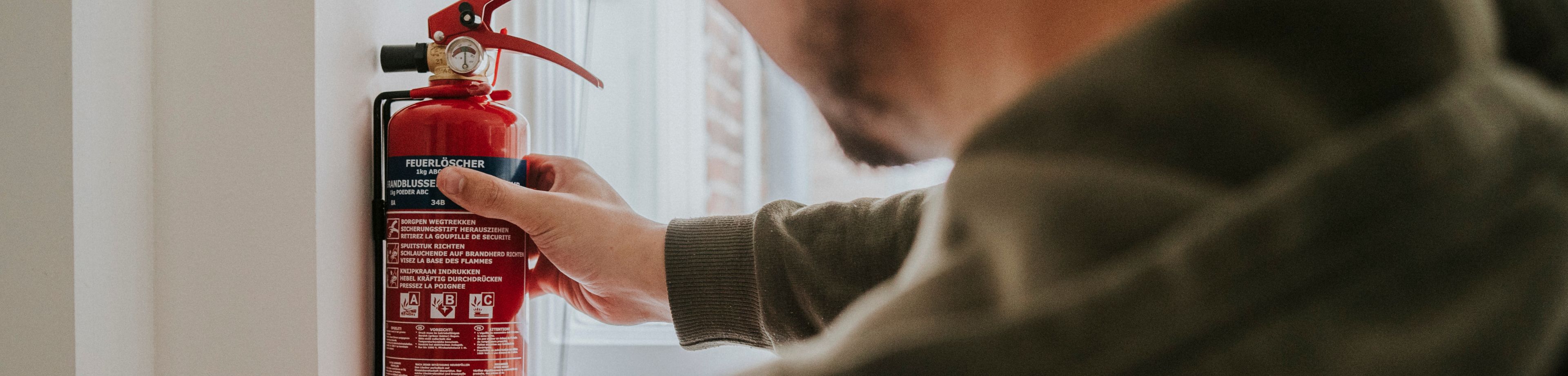 Man pakt een brandblusser van de muur