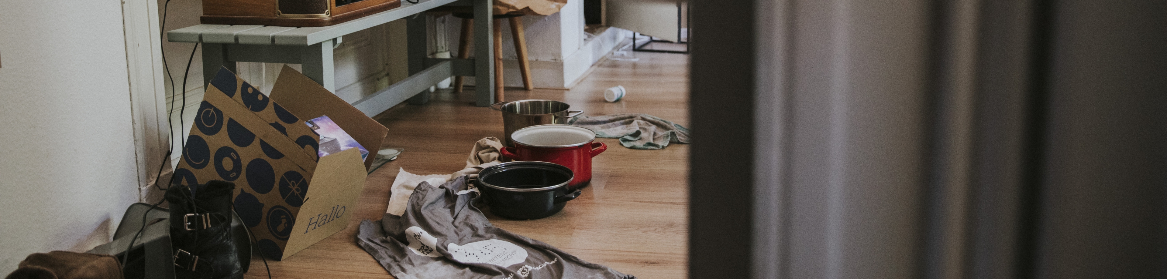 Pannen en handdoeken vangen water op wat lekt, op een laminaatvloer