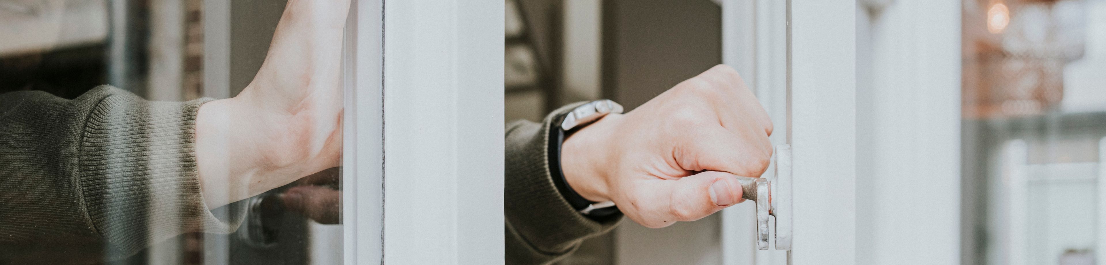 Hand sluit een open raam