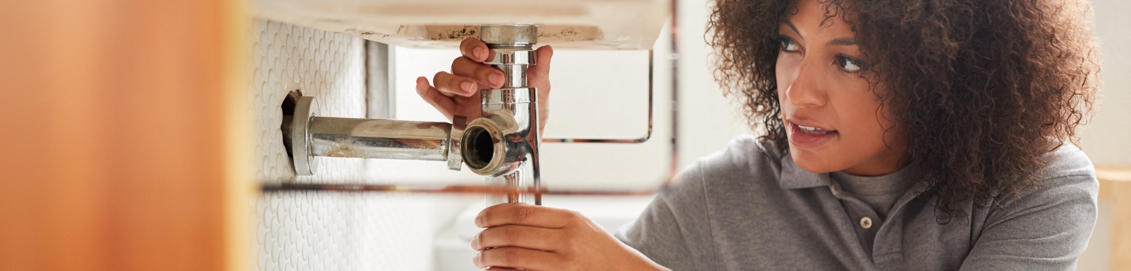 Vrouw heeft sifon vast onder de wasbak