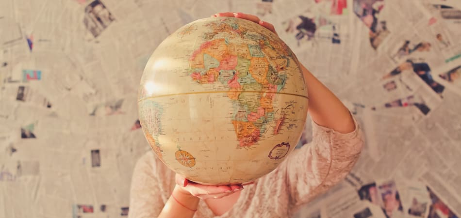 Vrouw houdt wereldbol vast voor haar hoofd.