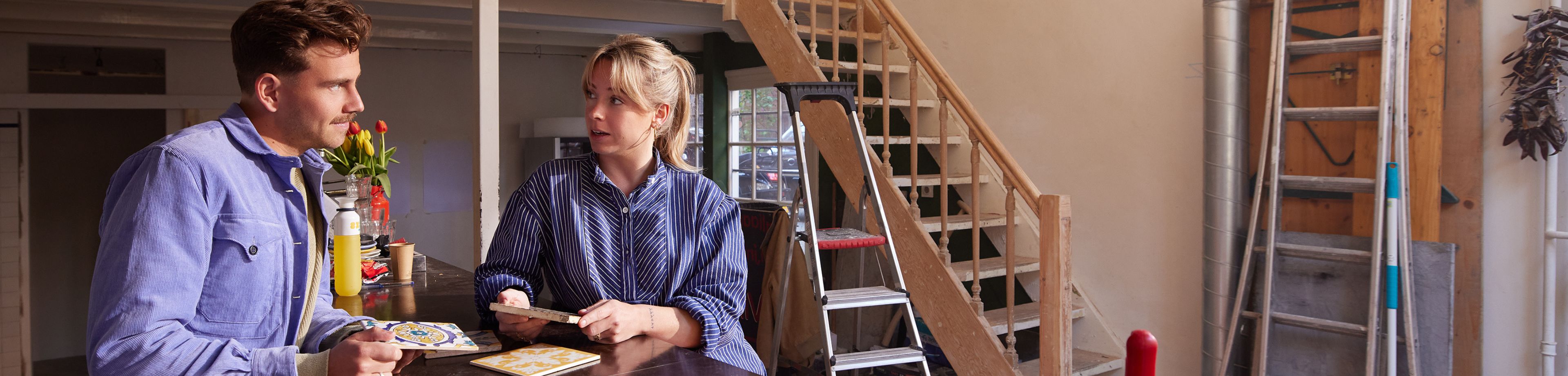 Een man en vrouw zijn samen tegels aan het uitzoeken voor hun bedrijfspand. 