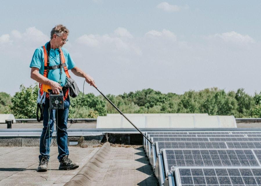 Man staat op het dak en controleert zonnepanelen