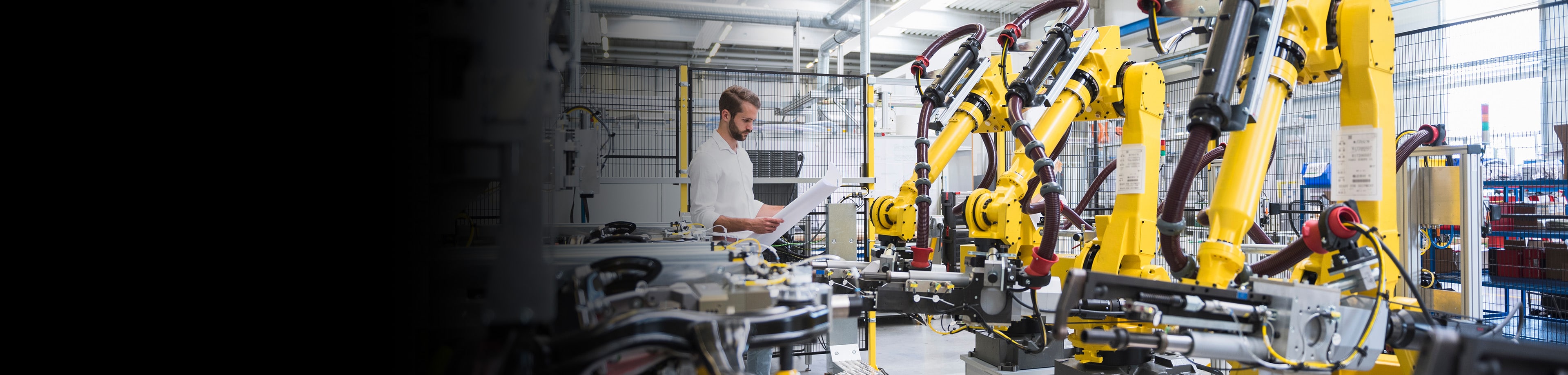 Man staat in bedrijfshal en werkt met robotarmen | Interpolis slimme oplossingen