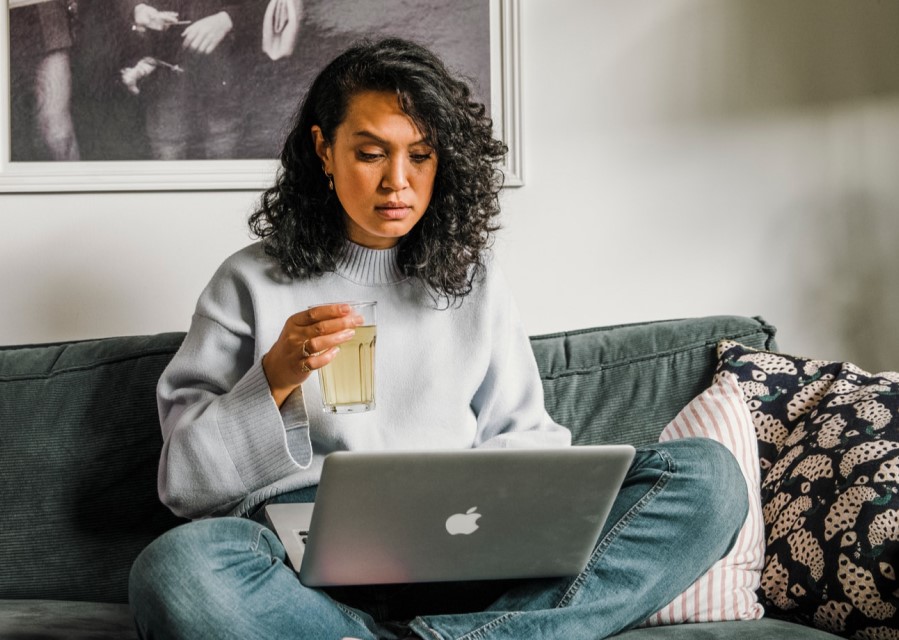 vrouw die op de bank zit en op haar laptop bezig is
