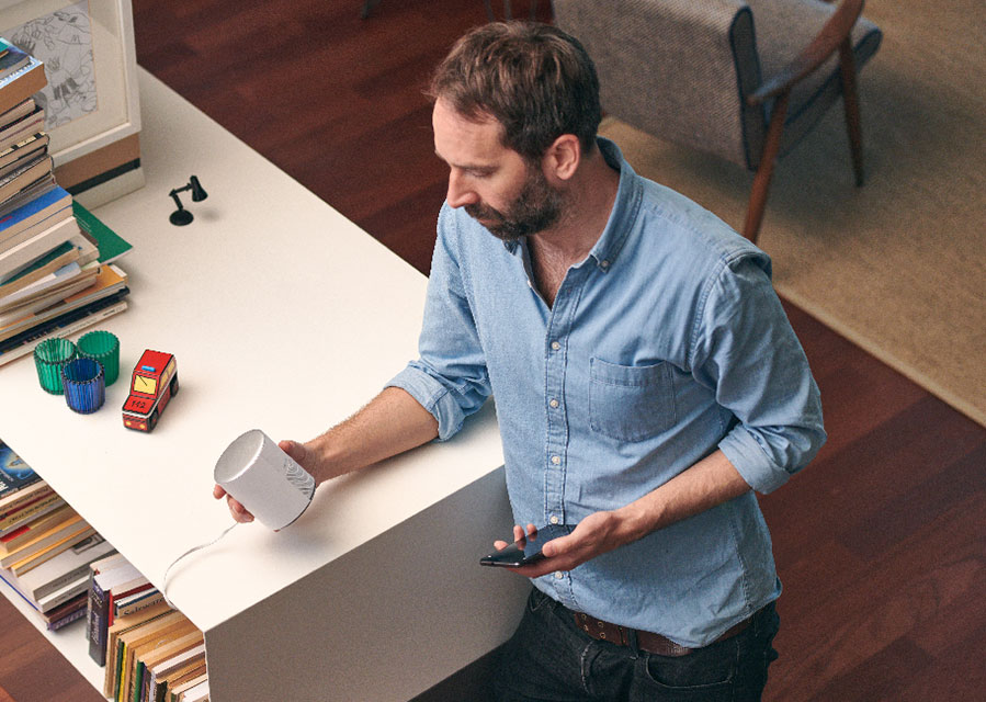 Man met alarmsysteem en mobiele telefoon in de hand. De camera heeft een privacymodus, zo weet je zeker dat niemand meekijkt als je thuis bent.